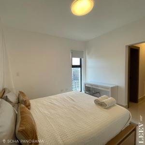 a bedroom with a large white bed with a window at Soha panorama- A14- 2 dormitorios in Santiago de los Caballeros