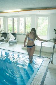 Eine Frau im Bikini steht neben einem Pool. in der Unterkunft Landhotel Neuhof in Zenting