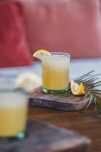 a glass of orange juice on a wooden table at Surfing Temple Hotel Boutique in General Luna