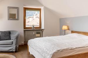 1 dormitorio con 1 cama, 1 silla y 1 ventana en Central Attic - City view, en Brunico