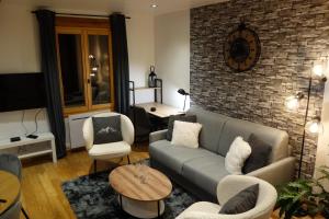 a living room with a couch and a brick wall at Chez petit Louis- Appart centre ville jusqu'à 6 personnes in Briançon