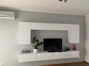 a living room with a tv on a white shelf at Apartament Rezydencja Metropolis ul.Dąbrowa 15 in Bydgoszcz