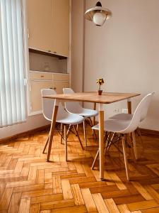 comedor con mesa de madera y sillas blancas en AMPLIO PISO VINTAGE EN ZONA CÉNTRICA DE MENDOZA. en Mendoza