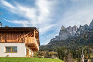a house on a hill with mountains in the background at Zu Grof Alpenglühn in Castelrotto
