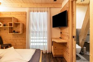 um quarto com uma cama, uma televisão e uma janela em Zu Grof Alpenglühn em Castelrotto