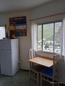 a kitchen with a table and a refrigerator and a window at Lagarto in Agaete