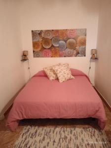 Un dormitorio con una cama roja con una pintura en la pared en Lagarto en Agaete