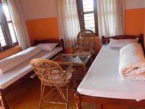 a room with two beds and a table and chairs at Rupa View Guest house in Pokhara