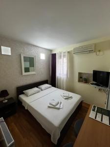 a bedroom with a large white bed and a television at Puerta Apartments in Kotor