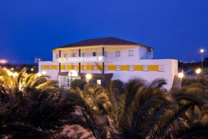 a building with palm trees in front of it at night at Première Classe Perpignan Nord in Rivesaltes