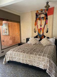 een slaapkamer met een bed met een schilderij van een vrouw bij Jnane Nina in Tagadirt