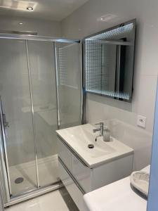 biała łazienka z prysznicem i umywalką w obiekcie Eider w Cannes