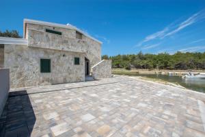 a stone building with a patio next to a body of water at Apartments-Sana-3 in Vir +1 photo