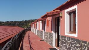 a row of buildings with windows and a walkway at Villa Rural Sierra Hueznar in El Pedroso