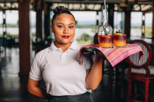 una mujer sosteniendo una bandeja con dos bebidas en una botella en Umaya Resort & Adventures en Maya Beach