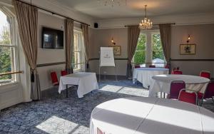 une chambre avec deux tables, des chaises et des fenêtres dans l'établissement Holmfield Arms by Greene King Inns, à Wakefield