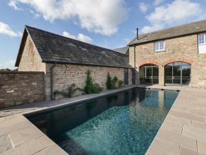 a swimming pool in front of a brick building at Pentwyn Farm in Raglan