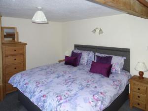 a bedroom with a bed with purple and purple pillows at Glan Wye in Rhayader