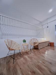 The Cozy Place by Nestcove في ميلاكا: كرسيين وطاولة في غرفة بجدران بيضاء