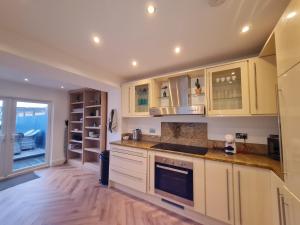 a kitchen with white cabinets and a wooden floor at Stylish & comfortable 4 bedroom home with patio & Secure Bike Storage in Merthyr Tydfil