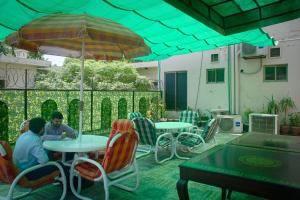 Premier Inn Grand Gulberg Lahore في لاهور: يجلس شخصان على الطاولات تحت مظلة