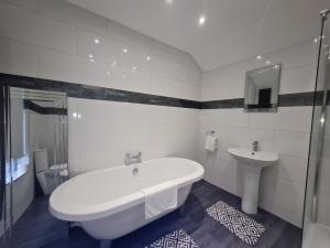 a white bathroom with a tub and a sink at Stylish & comfortable 4 bedroom home with patio & Secure Bike Storage in Merthyr Tydfil