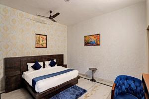 ein Schlafzimmer mit einem Bett und einem blauen Stuhl in der Unterkunft Jain Residency in Greater Noida