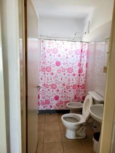 een badkamer met 2 toiletten en een roze douchegordijn bij Casa con pileta mirador de cabildo in La Punta