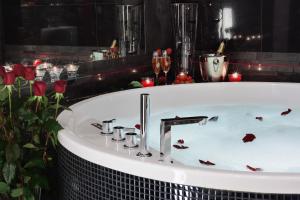 a bath tub with red flowers and candles in it at Komorowski Luxury Guest Rooms in Krakow