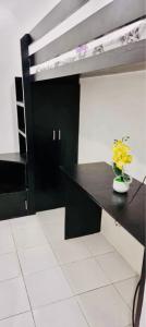 a black desk with a vase of yellow flowers on it at 2 BR staycation beside Enchanted Kingdom in Santa Rosa