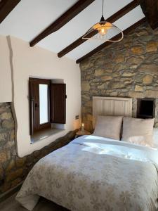 a bedroom with a bed and a stone wall at Casa Rural Vivienda Vacacional L´Curuxa Complejo CaleaCabo in Biescas