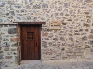 a stone building with a wooden door and a sign at Casa el Recreo in Jérica
