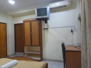 Habitación con escritorio y TV en la pared. en DP OBEROI RESIDENCY, en Ernakulam