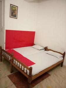 a bed in a room with a red and white bedspread at KRK ROOMS Kottarakara in Kottārakara