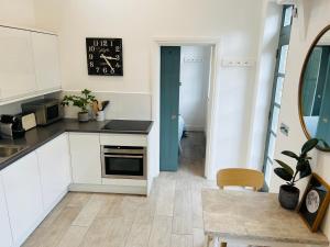 uma cozinha com armários brancos e um relógio na parede em Forge Cottage - Pretty 1 Bedroom Cottage with Free Off Street Parking em Londres