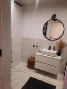 a white bathroom with a sink and a mirror at Apartament centrum in Ciechocinek
