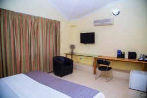 a hotel room with a bed and a desk and a television at Airside Hotel in Accra