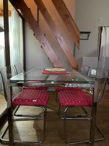 a glass table with two red chairs in a room at OpenSpace Vista Panoramica in Abetone