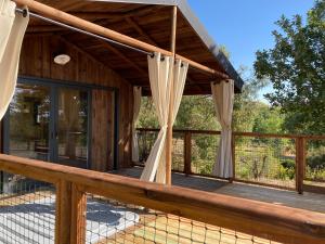 a wooden deck with curtains on a house at Cabanes Trésors de Campagne,spas privatifs in Villarzel-du-Razès