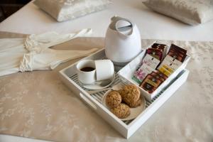 un vassoio con una tazza di caffè e biscotti su un letto di Unicum Roma Suites a Roma
