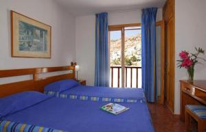 een slaapkamer met 2 blauwe bedden en een balkon bij Apartamentos Montecarlo in Puerto Rico de Gran Canaria