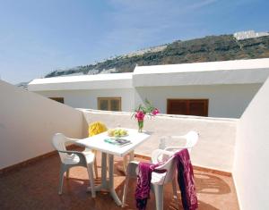 - Balcón con mesa blanca y sillas en Apartamentos Montecarlo, en Puerto Rico de Gran Canaria