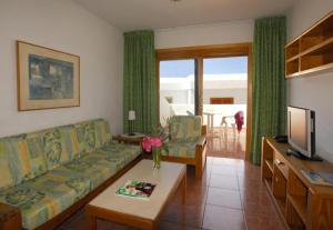 a living room with a couch and a tv at Apartamentos Montecarlo in Puerto Rico de Gran Canaria