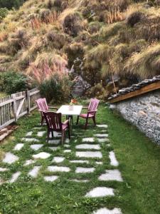 3 Stühle und ein Tisch auf einem Rasen mit Berg in der Unterkunft Casetta AnnyCa in Bourg-Saint-Pierre