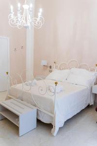 um quarto branco com uma cama branca e um lustre em A casa dei miei em San Pietro Vernotico