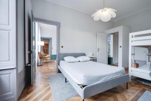 biała sypialnia z łóżkiem i krzesłem w obiekcie Grand appartement 8 personnes terrasse privative hyper centre calme w mieście Lons-le-Saunier +31 zdjęć