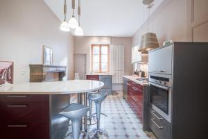 duża kuchnia z białym blatem i stołkami w obiekcie Grand appartement 8 personnes terrasse privative hyper centre calme w mieście Lons-le-Saunier