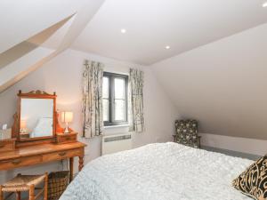 1 dormitorio con cama, espejo y escritorio en Nine Acres Barn en Marlborough