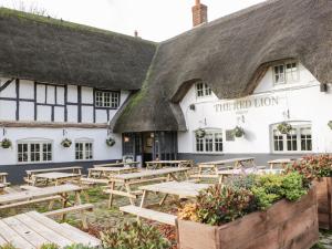 a pub with wooden tables in front of a thatched building at Nine Acres Barn in Marlborough