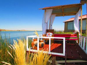 eine Terrasse mit einem Bett und einem Tisch neben dem Wasser in der Unterkunft Titicaca Uros Summa Paqari in Uros